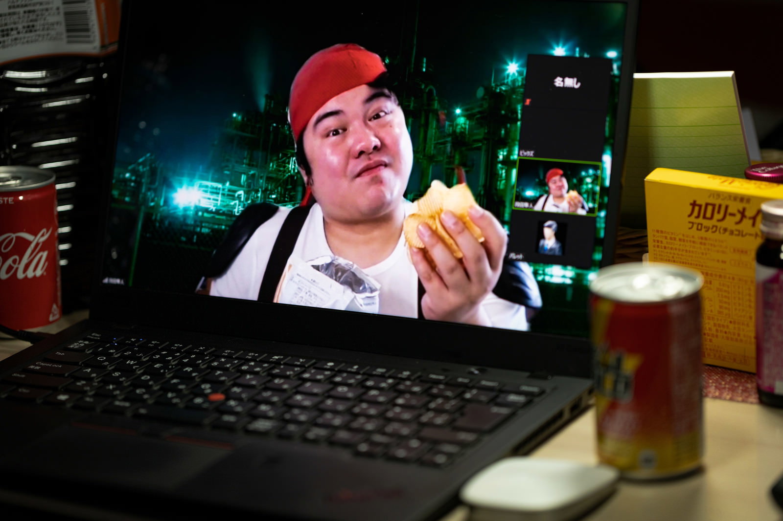 ノートパソコンでビデオ通話をしながらポテトチップスを食べるコスプレ男性［モデル：段田隼人］