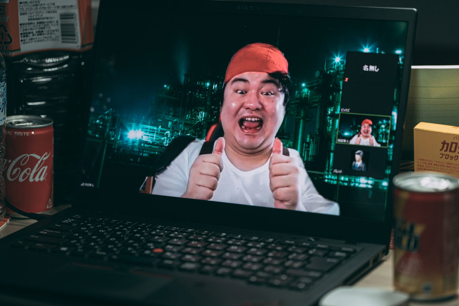 ノートパソコンの画面に映る赤いニット帽の男性がサムズアップポーズ［モデル：段田隼人］