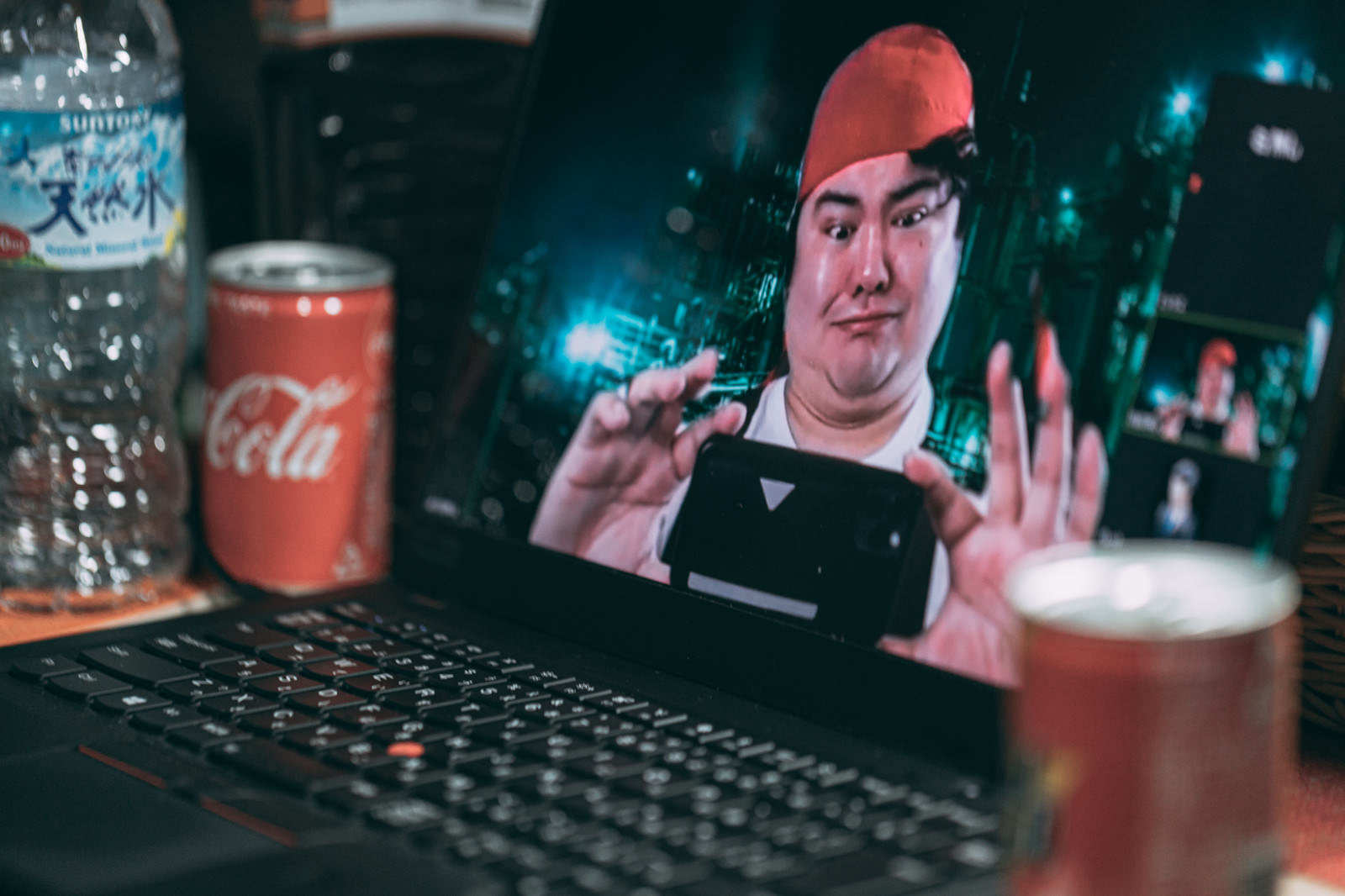 赤いバンダナの男性がノートPCに向かってスマホでスクショを撮る様子［モデル：段田隼人］