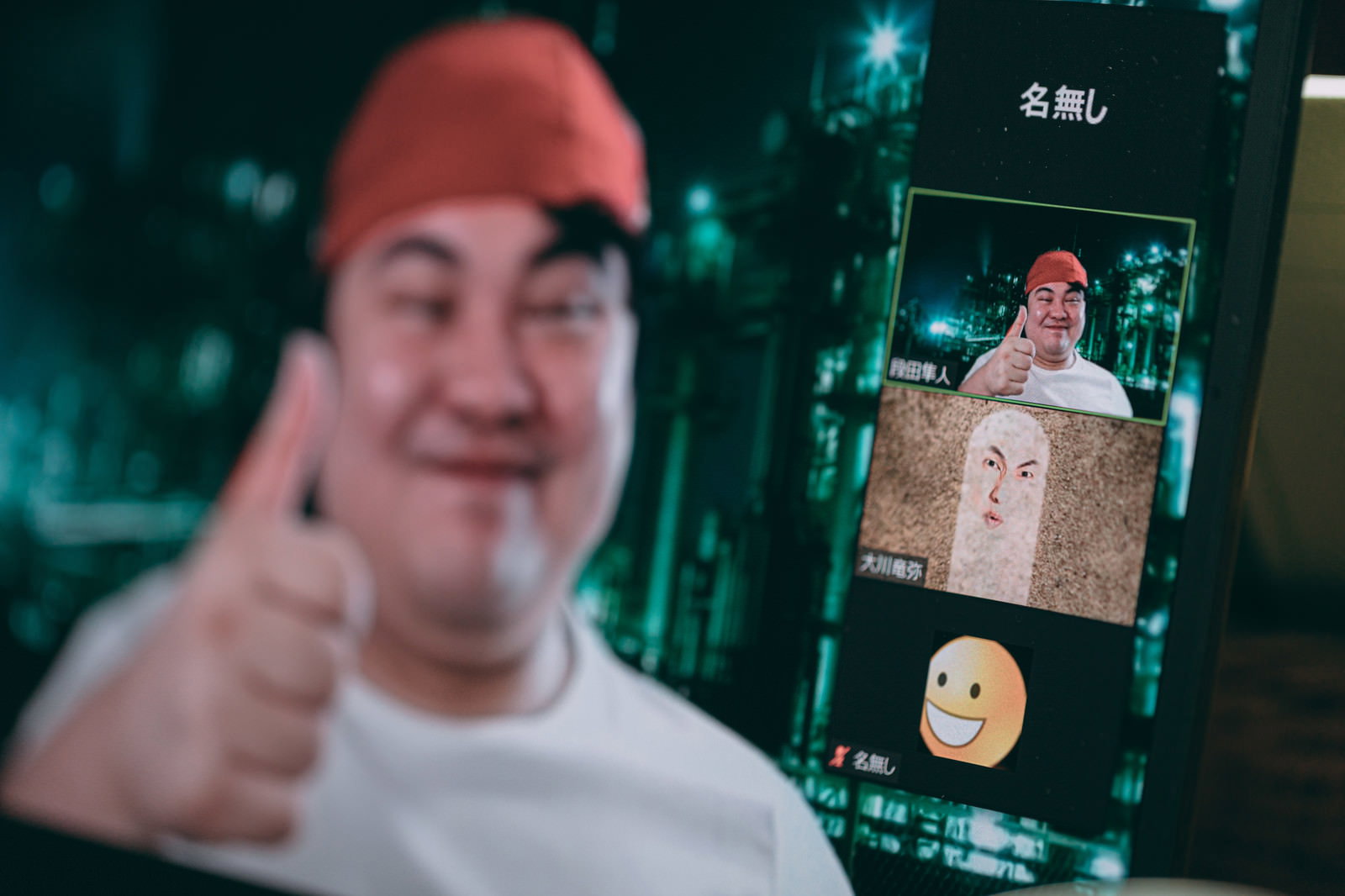 赤い帽子をかぶった男性がスマホを持ち親指を立ててグッジョブのサインをしている様子［モデル：段田隼人］