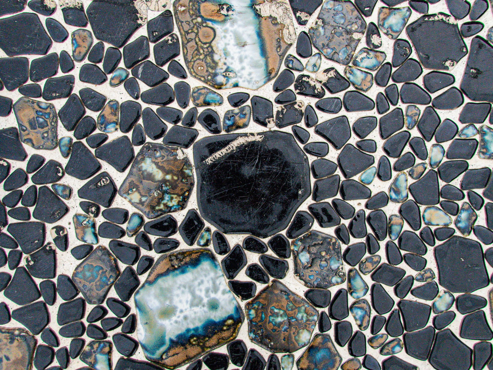 Textured gray concrete surface with embedded stones and aggregates, giving a glossy appearance