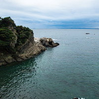 造船跡の岩場に茂る木々と海岸風景の写真