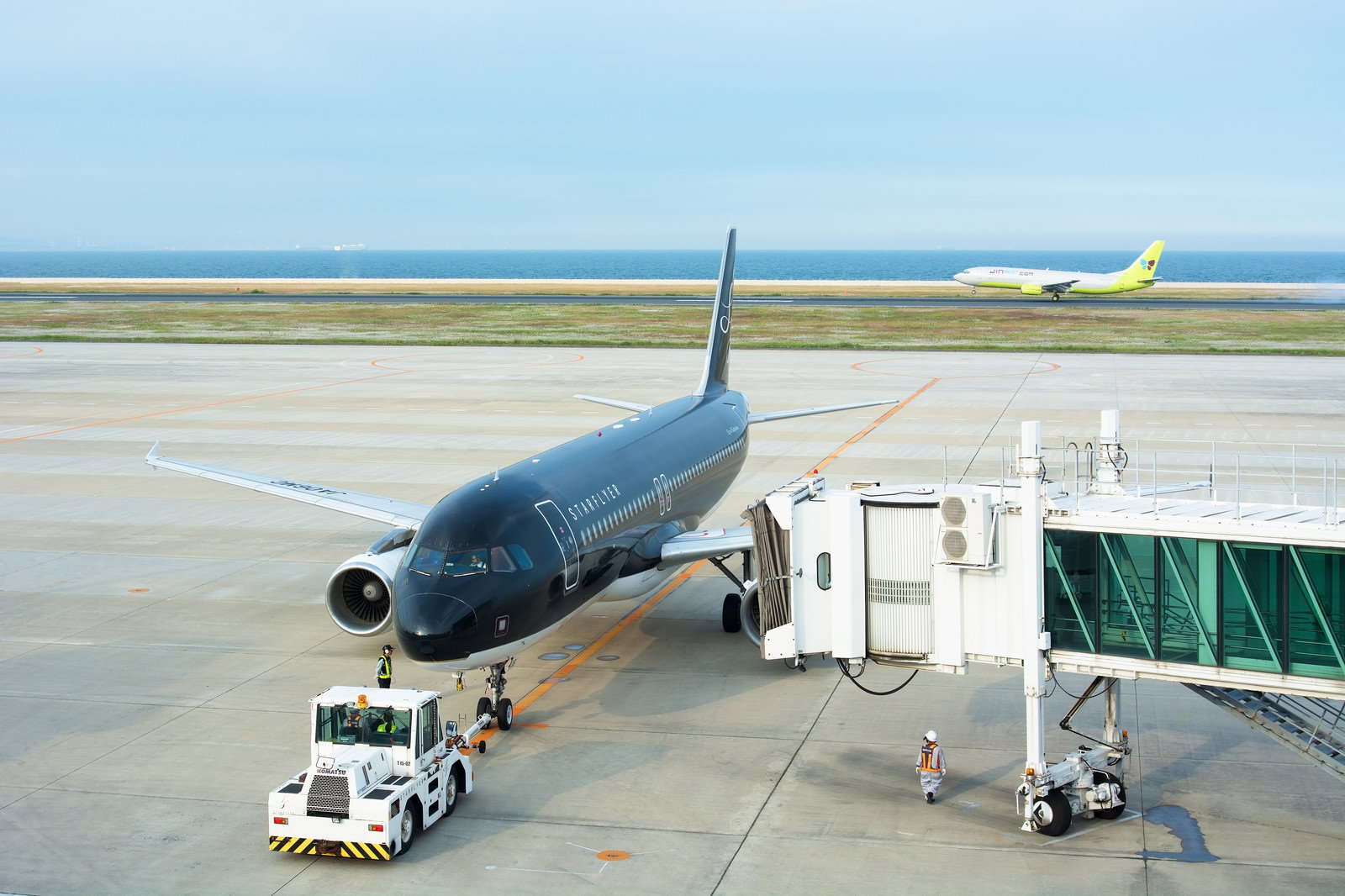 ボーディングブリッジが外されプッシュバックされる青い旅客機