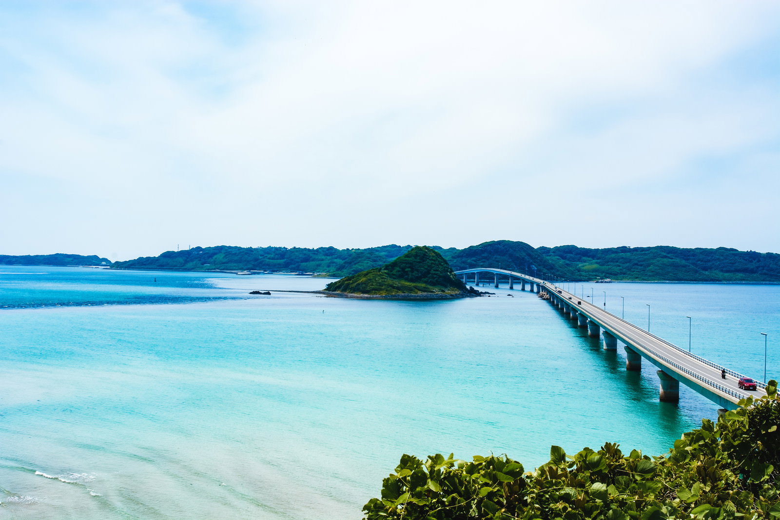 山口県下関の角島大橋を南側展望台から眺めた風景。エメラルドグリーンの海上に白い橋が伸びている。