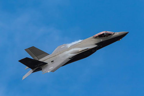 快晴の青空を背景に飛行する最新鋭ステルス戦闘機
