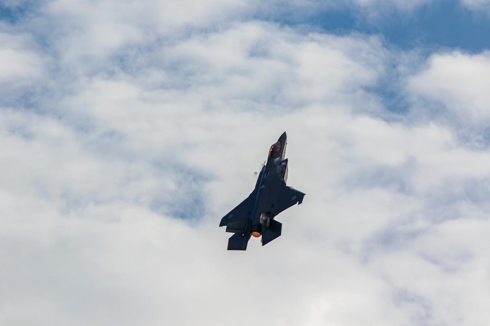 Japan Air Self-Defense Force fighter jet flying with afterburner between the blue sky and clouds