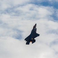 青空と雲の間を飛行する航空自衛隊の戦闘機の写真