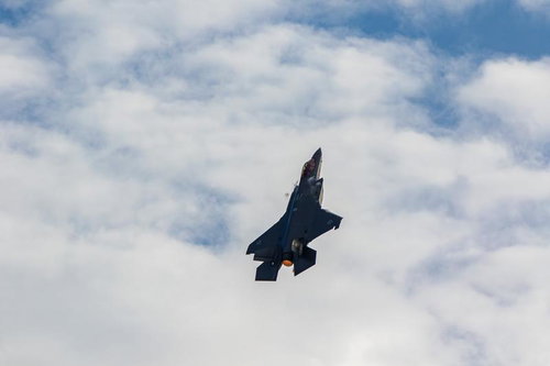 青空と雲の間を飛行する航空自衛隊の戦闘機