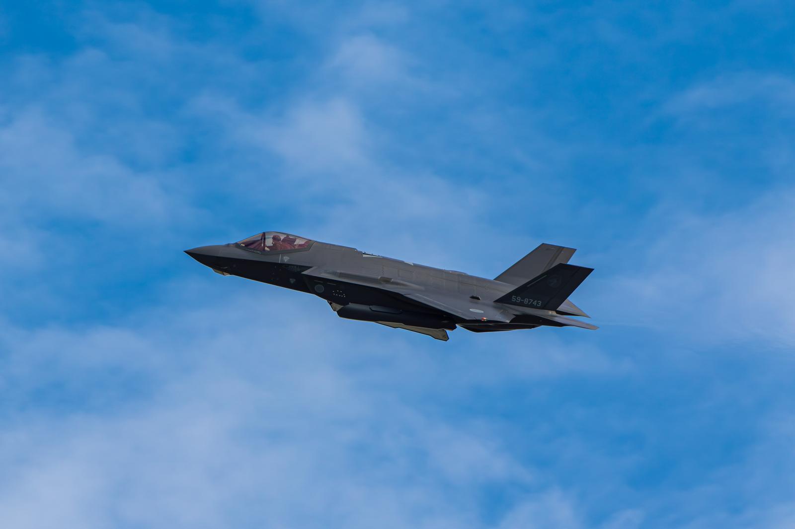Gray stealth fighter jet of the Japan Air Self-Defense Force flying in the blue sky with white clouds
