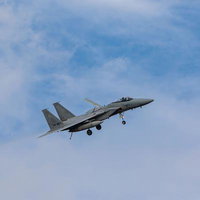 晴れた空に白い雲が浮かぶ中を飛行する航空自衛隊の戦闘機の写真