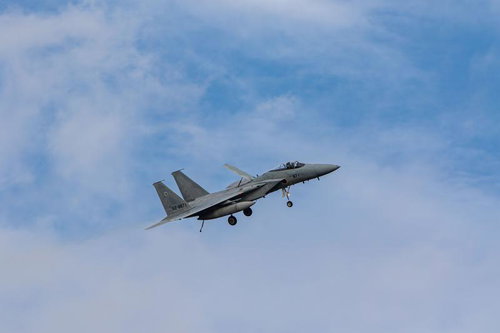 晴れた空に白い雲が浮かぶ中を飛行する航空自衛隊の戦闘機