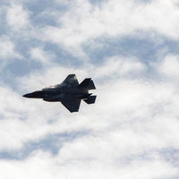 曇り空を背景に飛行する航空自衛隊のF-35ライトニング戦闘機の写真