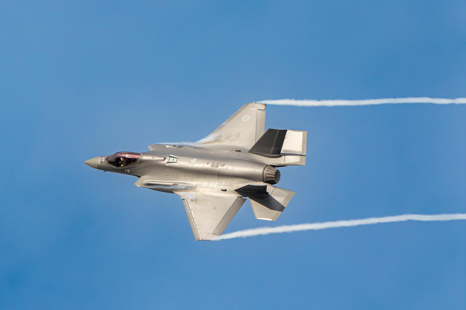 青空を高速飛行する航空自衛隊の戦闘機と白い航跡