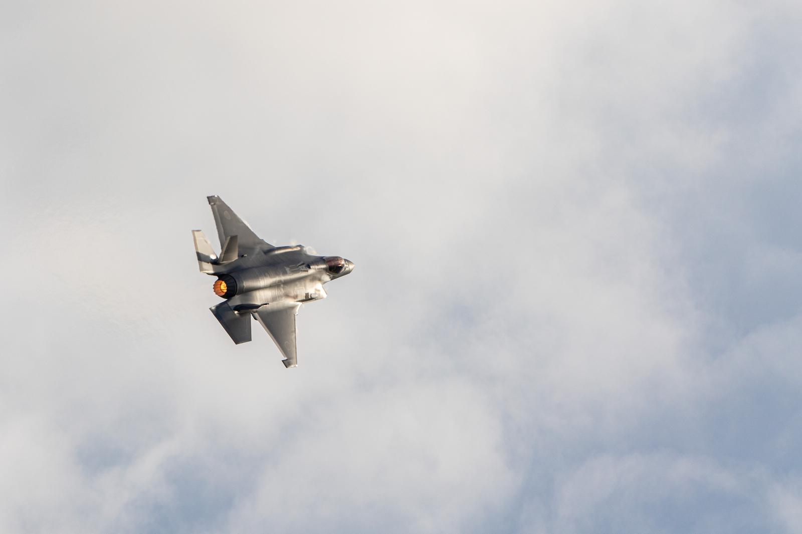 Japan Air Self-Defense Force fighter jet flying through the overcast sky with afterburner