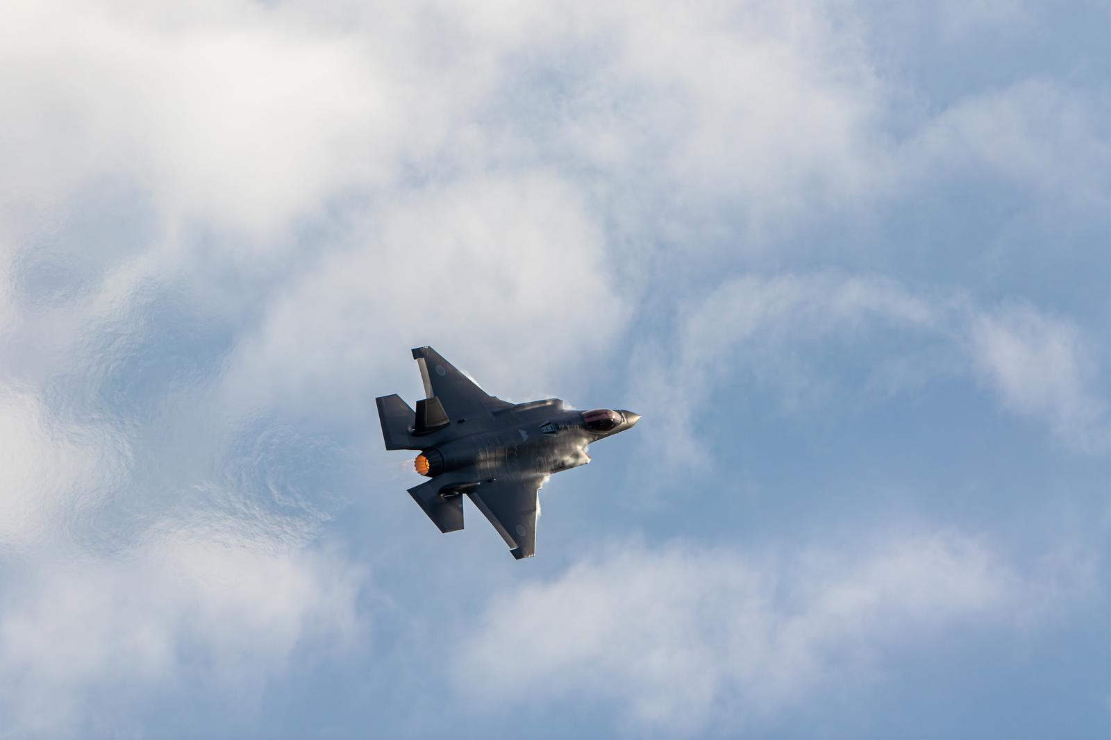 青空と白い雲の間を飛行する航空自衛隊のF-35戦闘機