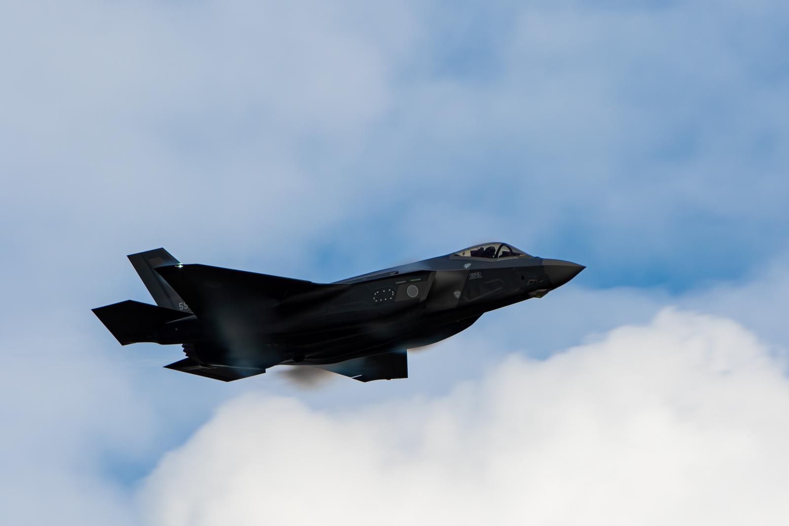 Gray fighter jets flying against the backdrop of a blue sky and clouds.