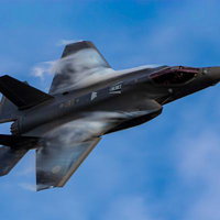 青空を背景に高速飛行するステルス戦闘機の写真