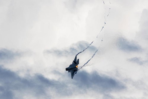 白い雲に包まれた空を飛行する航空自衛隊の戦闘機