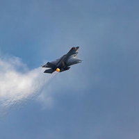 青空と雲の間を飛行する航空自衛隊のステルス戦闘機F-35の写真