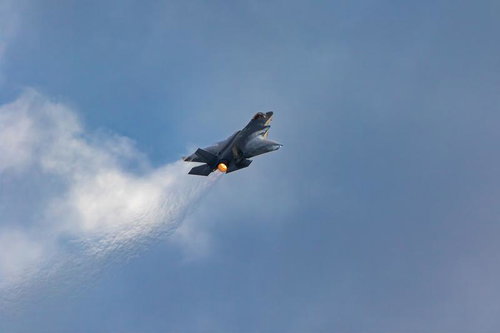 青空と雲の間を飛行する航空自衛隊のステルス戦闘機F-35