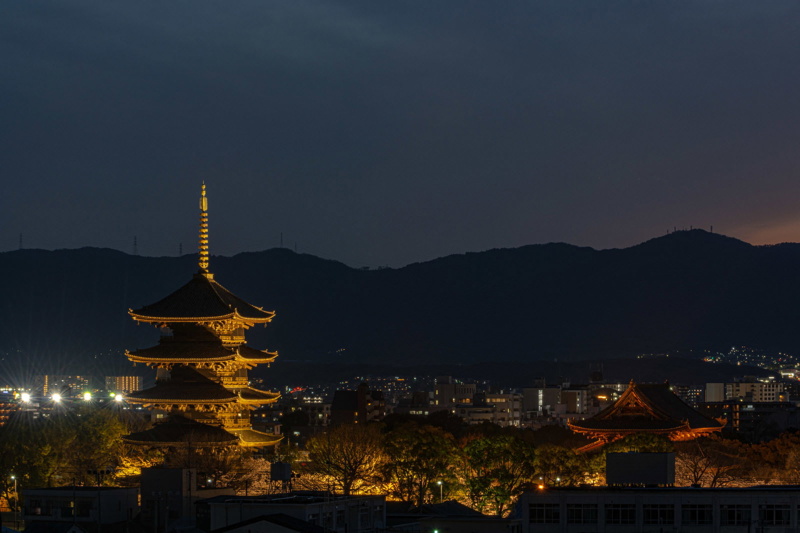 夕暮れの空に浮かぶライトアップされた東寺の五重塔と京都の街並み