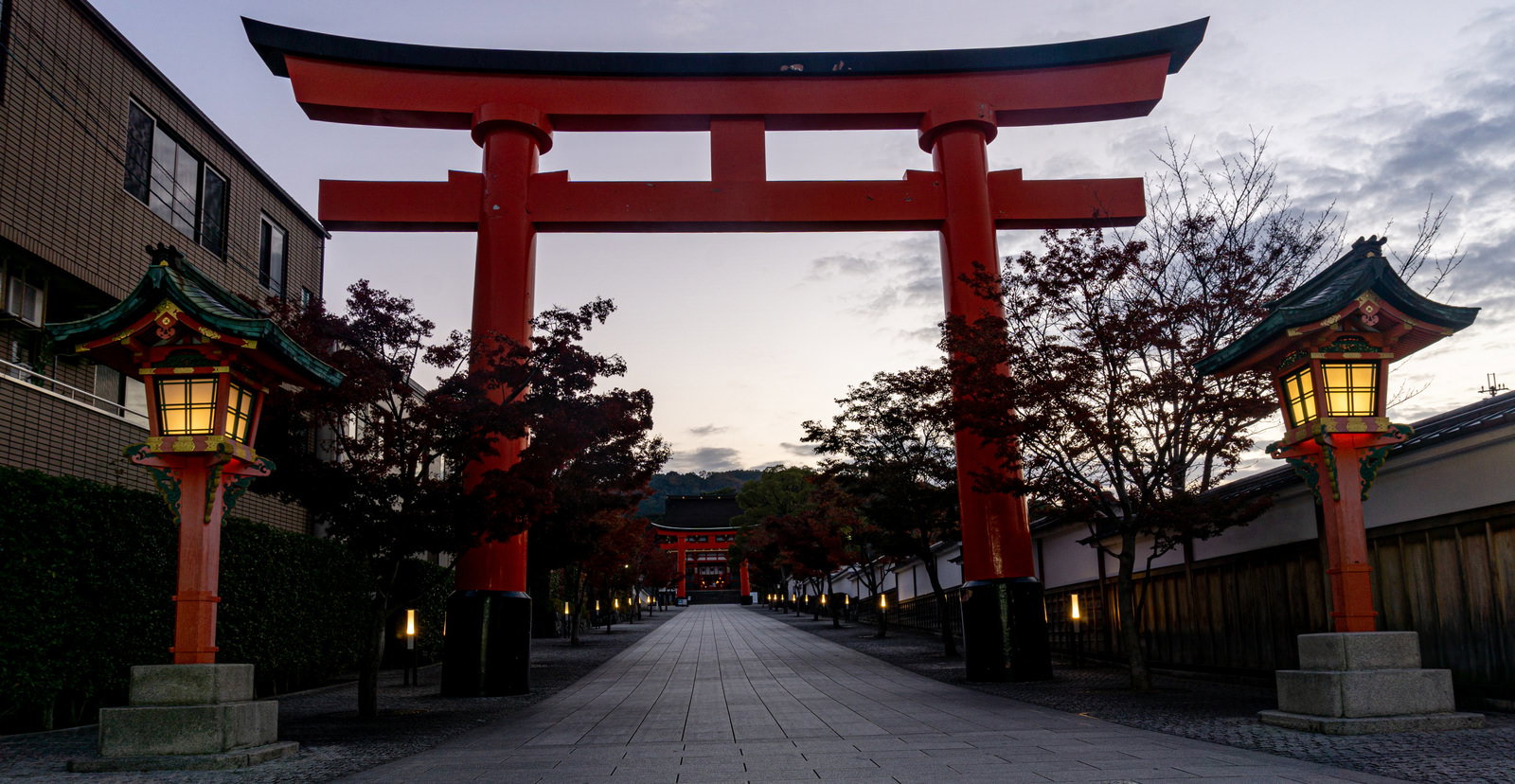 伏見稲荷大社の朱色の鳥居と石畳の参道、両脇に並ぶ灯篭