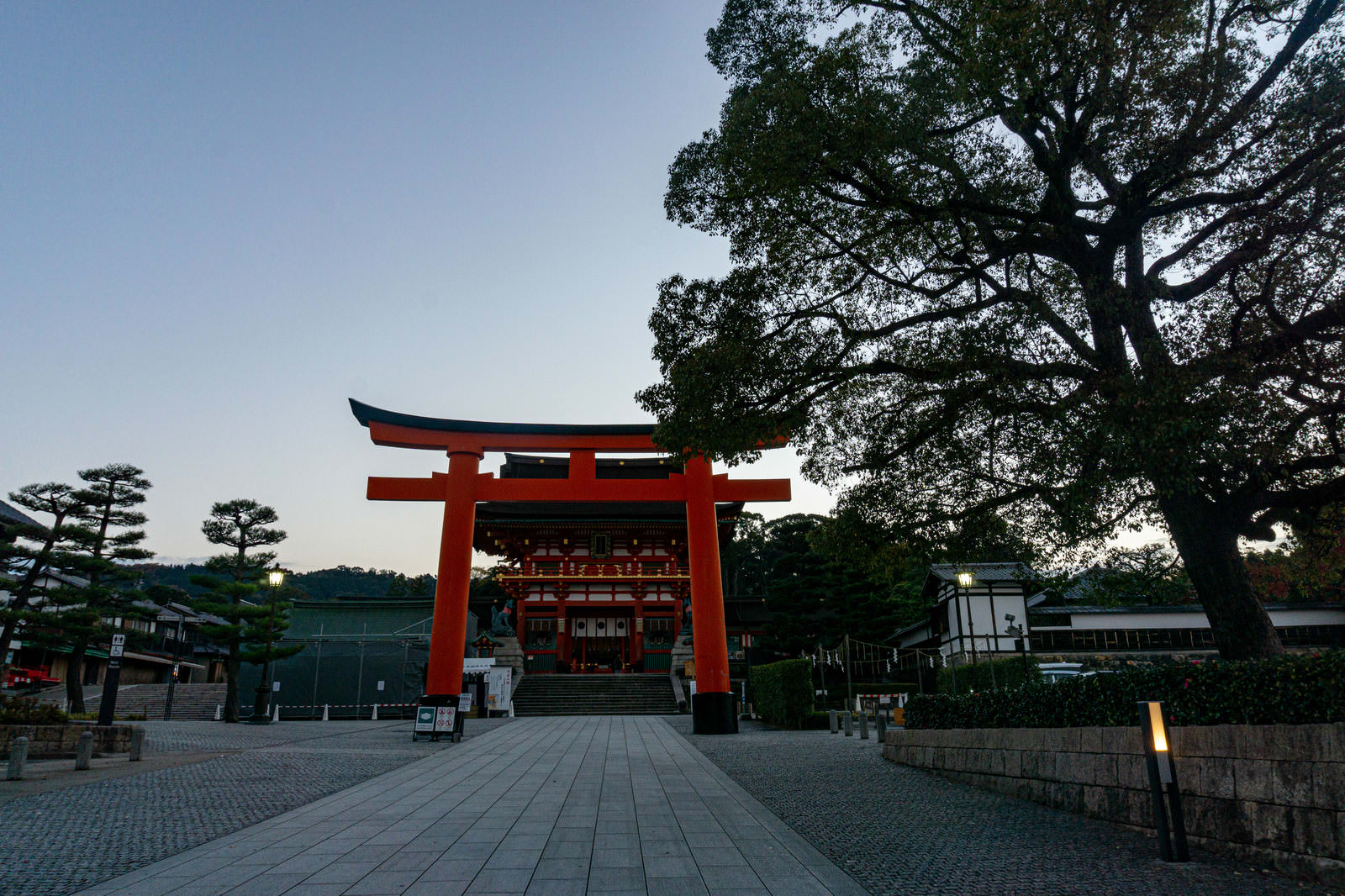 伏見稲荷大社の参道にそびえ立つ赤い二番鳥居と楼門を石畳から撮影した朝の風景