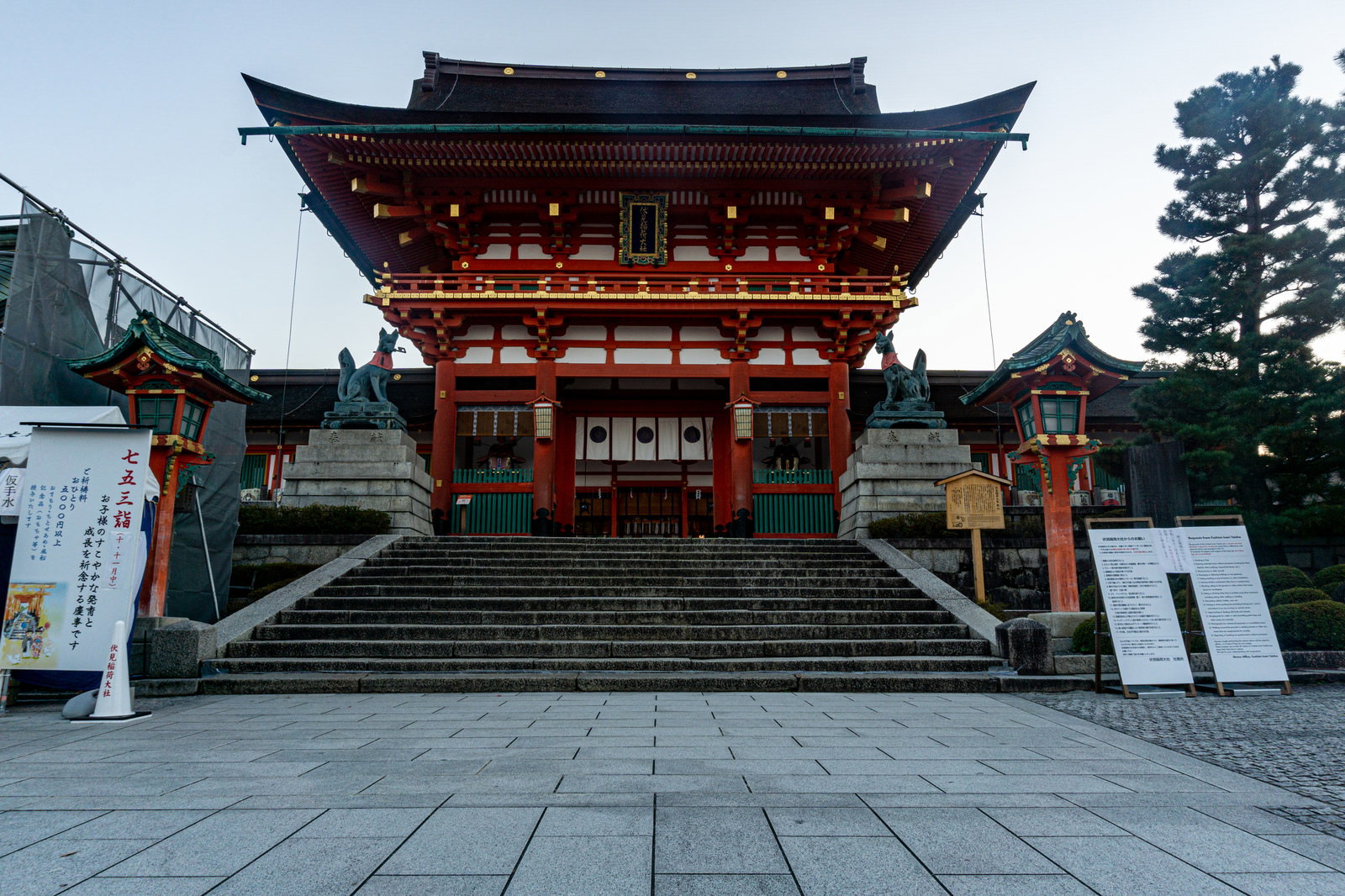 石段の上に建つ伏見稲荷大社の朱色の楼門と薄明かりの空