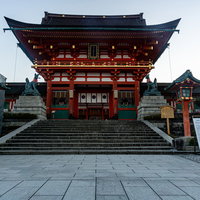 白み始めた東の空の前に立つ伏見稲荷大社・楼門の写真