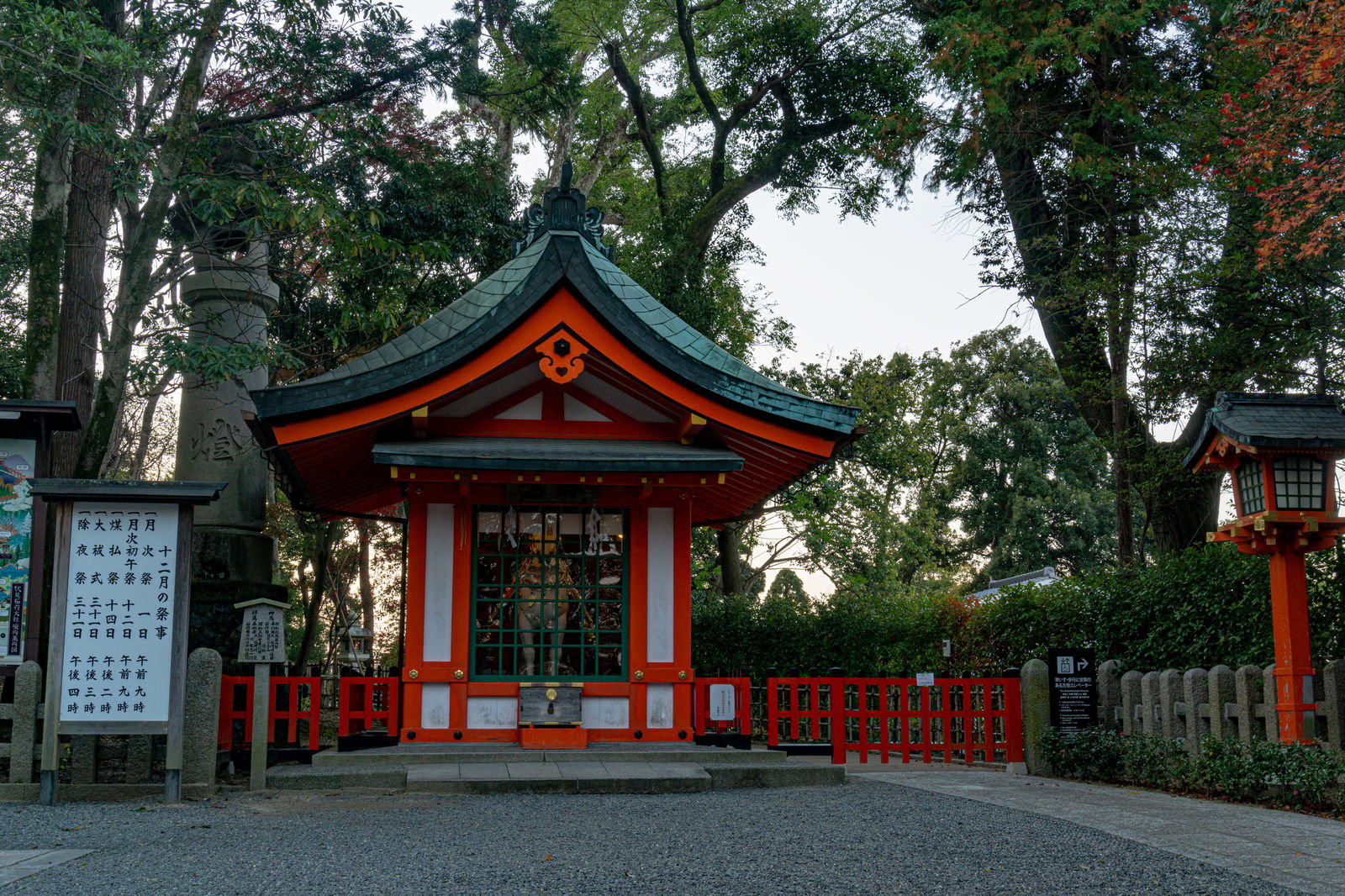 朱色の壁と黒い屋根の伏見稲荷大社・神馬舎。周囲は樹木に囲まれている