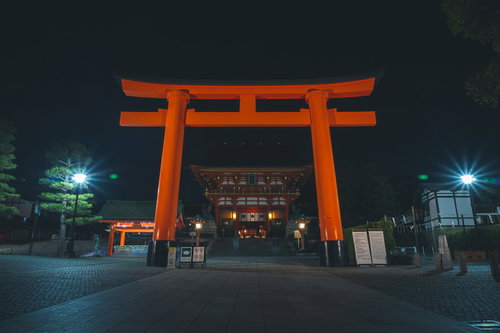 夜間ライトアップされた朱色の大鳥居と石畳の参道