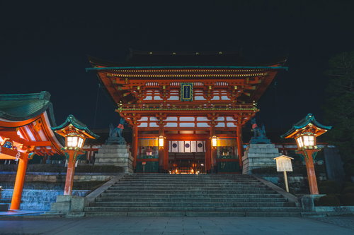 夜間ライトアップされた朱塗りの伏見稲荷大社楼門と石段