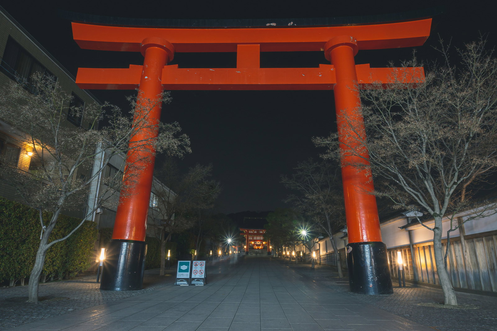夜の伏見稲荷大社の朱色の一番鳥居と石畳の参道