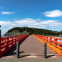 青い空と海に映える朱色が美しい雄島橋の写真