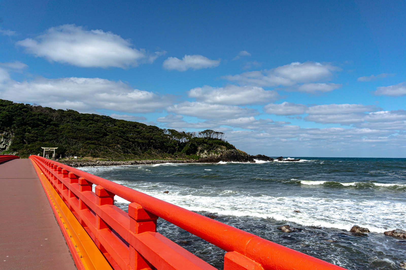 雄島橋の赤いガードレールと青い海に寄せる白波が見える海岸風景