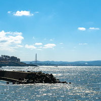 雄島橋近くの堤防の向うに霞んで見える東尋坊や福井臨海工業地帯の写真