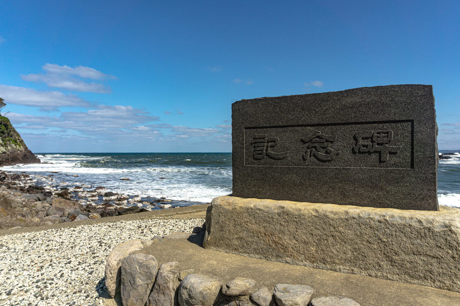 雄島橋近くの海岸に建てられた石の記念碑と青い海