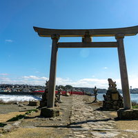 大きな石の鳥居越しに見る対岸の風景の写真