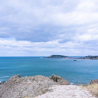 東尋坊の岩場へと続く石畳の先に見える雄島の写真