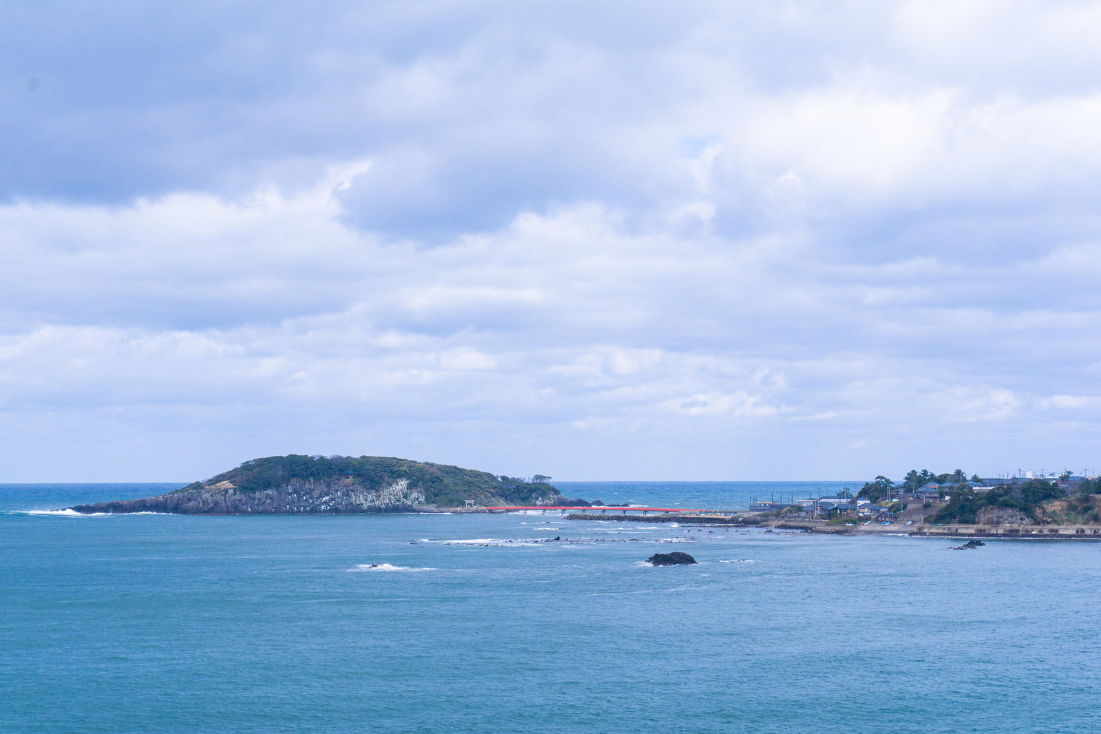 東尋坊から見た雄島と赤い橋、青い海と曇り空の風景