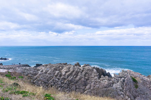 特徴的な姿を見せる東尋坊と小さく見える観光客