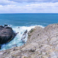 荒天のために遊覧船のいない東尋坊遊覧船乗り場とそこへと続く階段を別の岩場から見るの写真