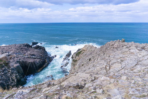 荒天のために遊覧船のいない東尋坊遊覧船乗り場とそこへと続く階段を別の岩場から見る