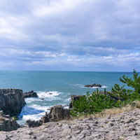 東尋坊の遊歩道から見る日本海と北西からの波に向かって進む軍艦や潜水艦に見える軍艦岩の写真