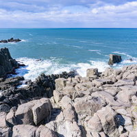 柱状節理の特徴がわかる柱を束ねたような岩場の上部に立ち日本海を眺めるの写真