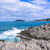 柱状節理の岸壁の先端で弾ける寄せる波の写真