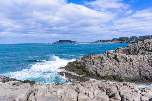 柱状節理の岸壁の先端で弾ける寄せる波