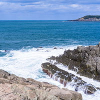 押し寄せる波が東尋坊の岩々にぶつかり白く泡立つの写真