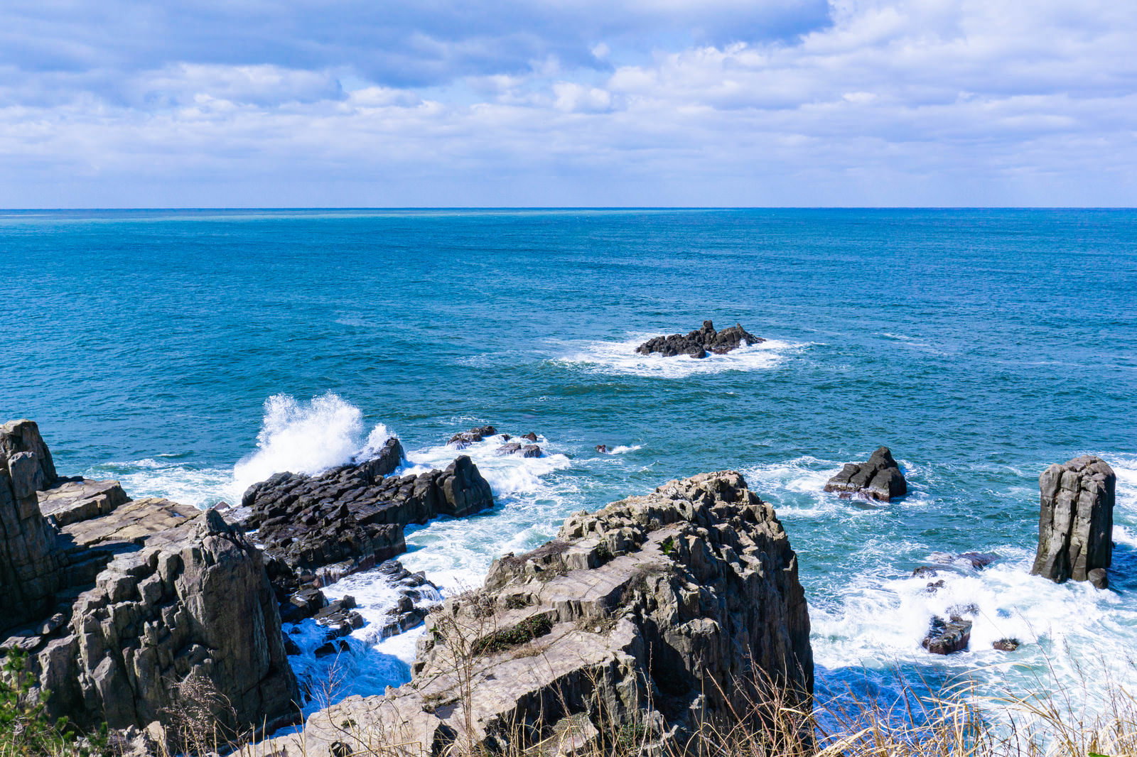 東尋坊の軍艦岩と三段岩の岩場で白い波しぶきが上がる海の風景