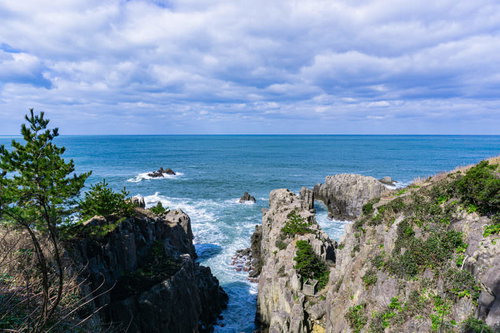 切り立った岩壁の間に打ち寄せ白く泡立つ波